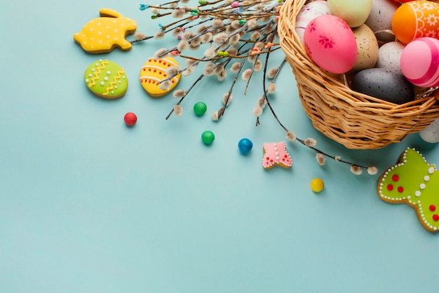 Free photo high angle of easter eggs in basket with bunny and butterfly shapes