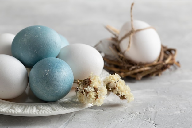 High angle of easter eggs in bird nest with plate and flowers