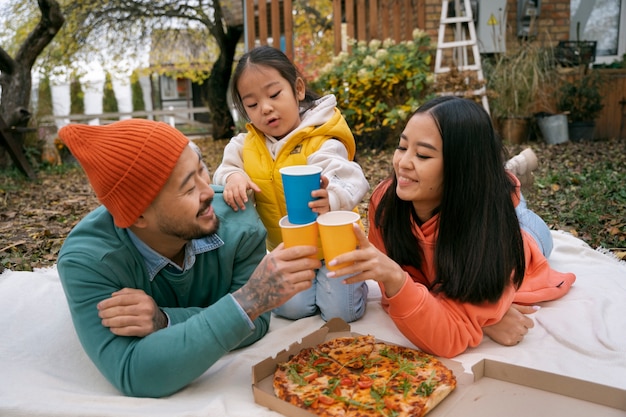 Free photo high angle family eating pizza outdoors