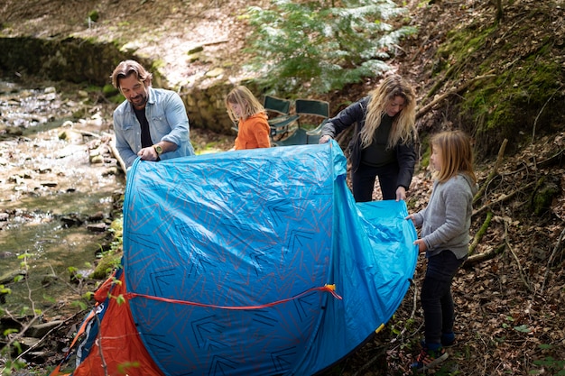 Free photo high angle family setting up the tent