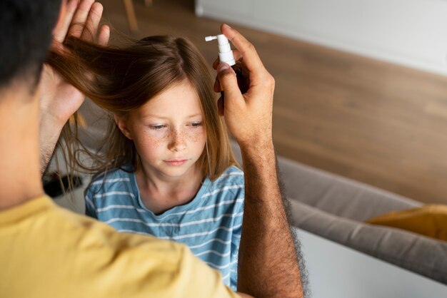 High angle father using lice treatment for girl