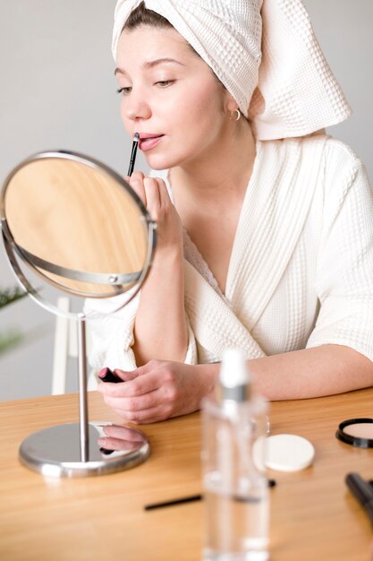 High angle female applying lipstick