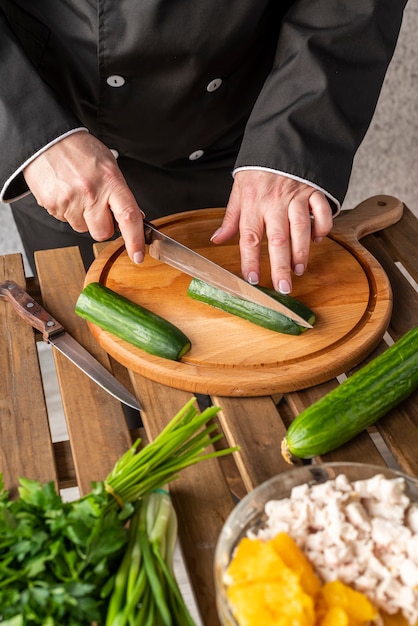 High angle of female chef cutting cucumbers