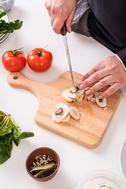 High angle of female chef cutting mushrooms