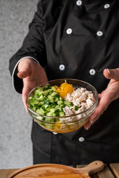 Free Photo high angle of female chef holding bowl with ingredients