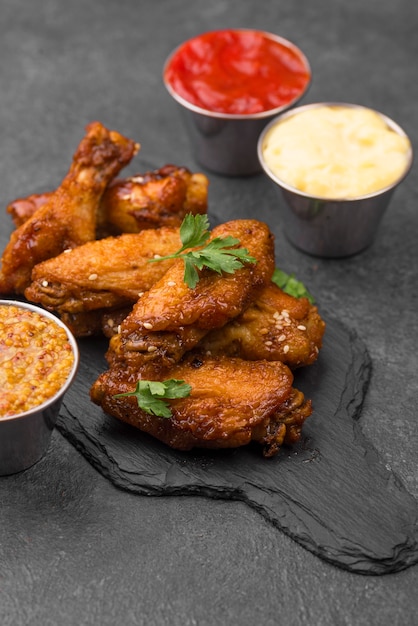 High angle of fried chicken on slate with variety of sauces