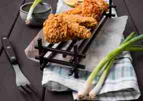 Free photo high angle fried chicken wings on tray with green onions and fork