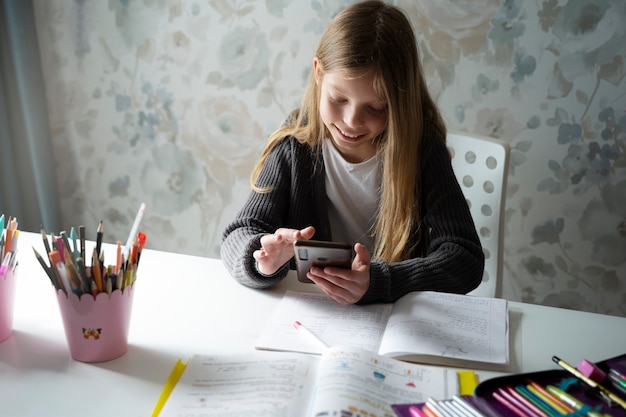 High angle girl doing homework with phone