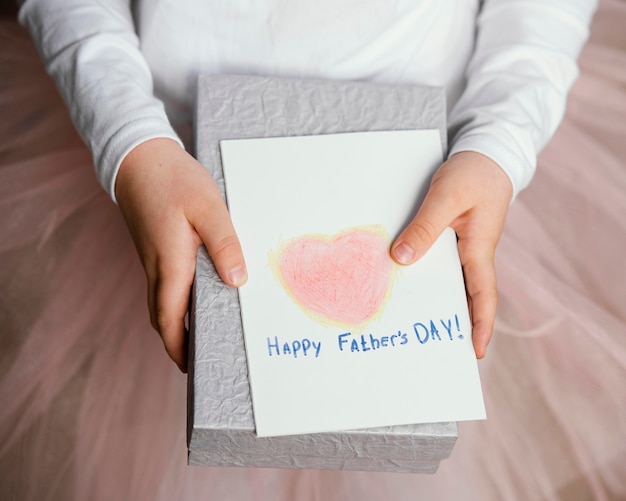 Free Photo high angle of girl holding present and card for father's day