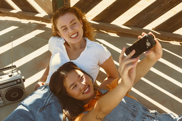 Free Photo high angle girls taking selfie with old phone