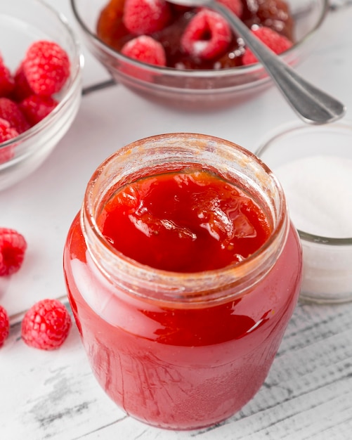 High angle of glass jar with raspberry jam and fruits