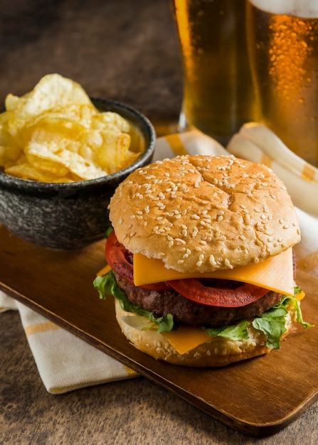 High angle of glasses of beer with cheeseburger and chips