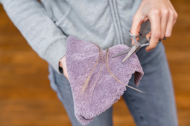 High angle of hairdresser holding cloth and scissors with tuft of hair