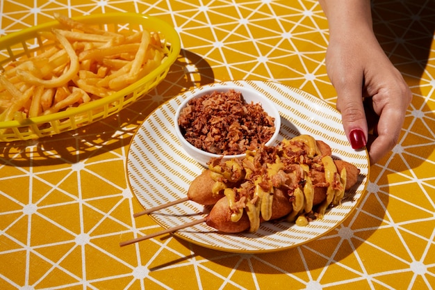 High angle hand holding plate with corn dogs