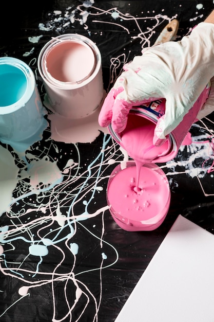 High angle of hand with glove using paint from cans