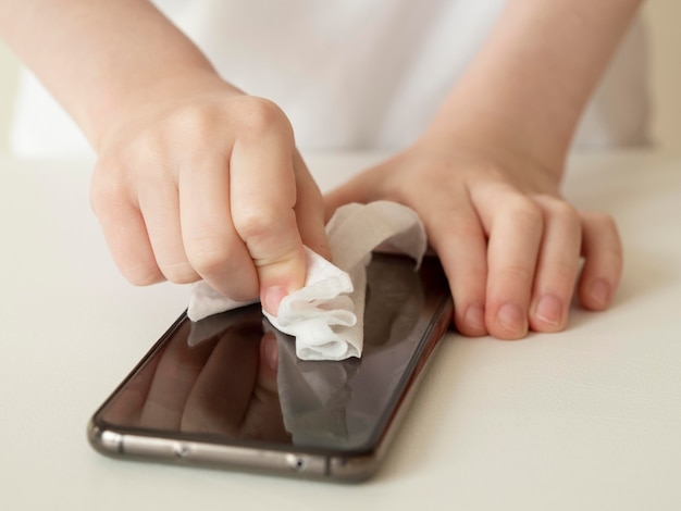 High angle of hands disinfecting smartphone