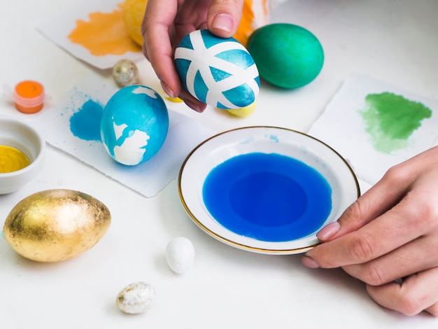 Free photo high angle of hands dyeing egg with design for easter