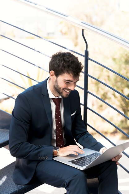 High angle happy man on stairs with laptop