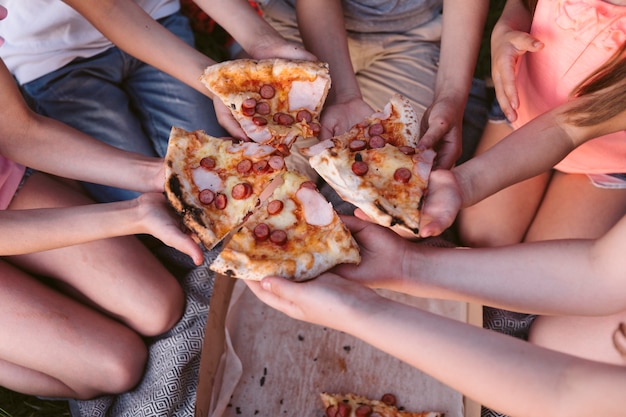 High angle kids taking a slice of pizza