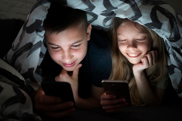 High angle kids with smartphones under blanket