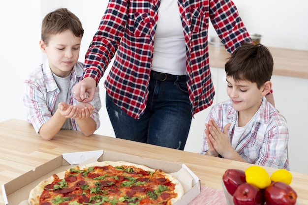 Free photo high angle of kinds sanitizing their hands before eating pizza