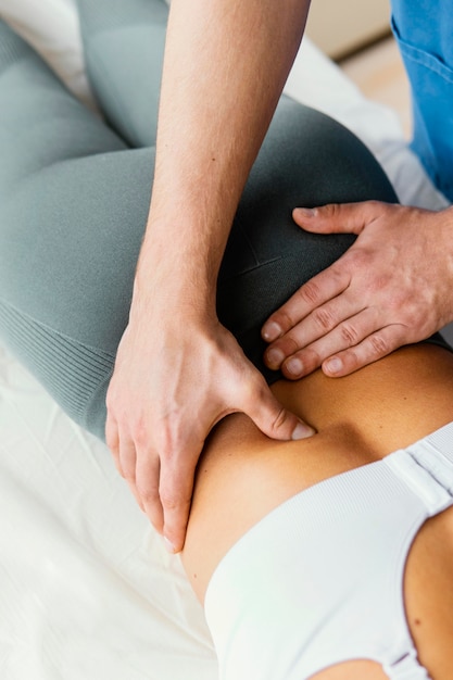 Free photo high angle of male osteopathic therapist checking female patient's lower back spine