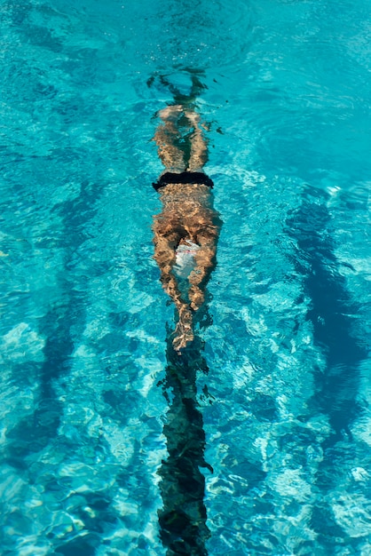 High angle of male swimmer swimming in water pool