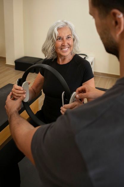 Free photo high angle man helping woman in pilates class