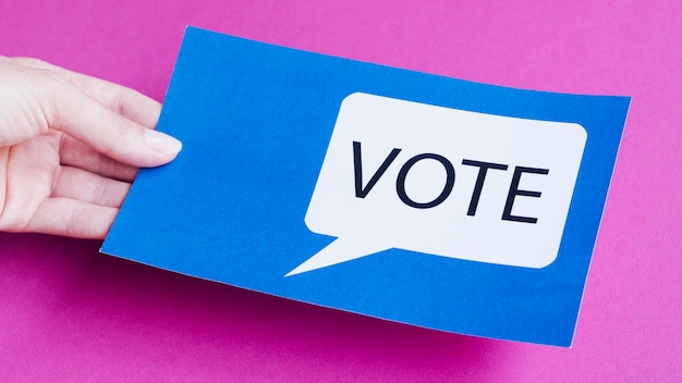 Free photo high angle man holding a blue card with vote speech bubble