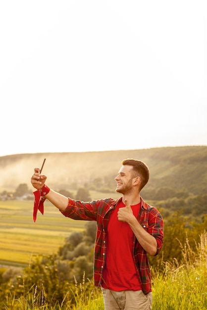 Free photo high angle man on mountain taking selfie