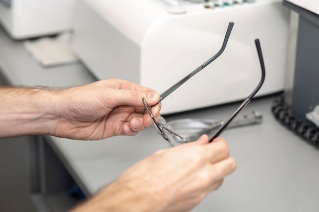 High angle of man picking up his glasses off of desk