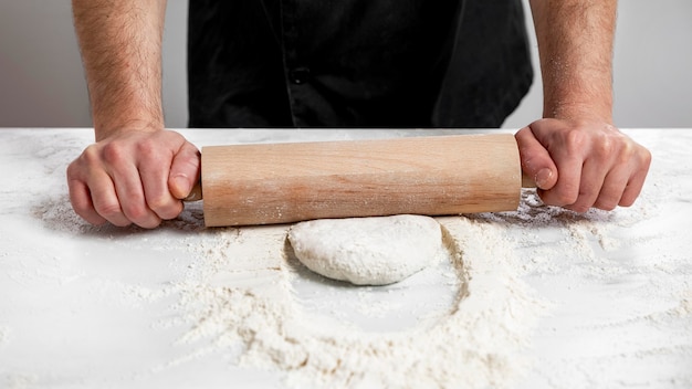 Free photo high angle man rolling pizza dough