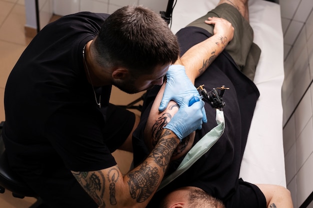 Free photo high angle man tattooing with gloves