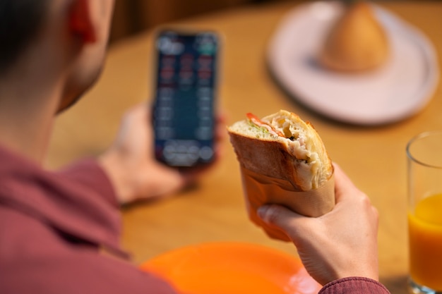 Free photo high angle man with  paper-wrapped sandwich