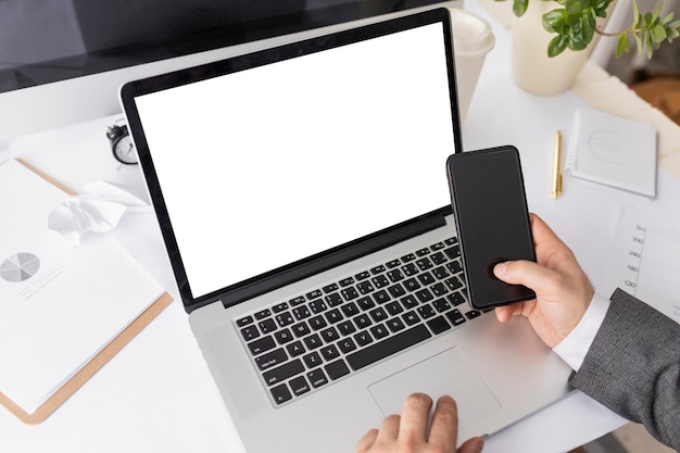 High angle man working on devices with empty laptop