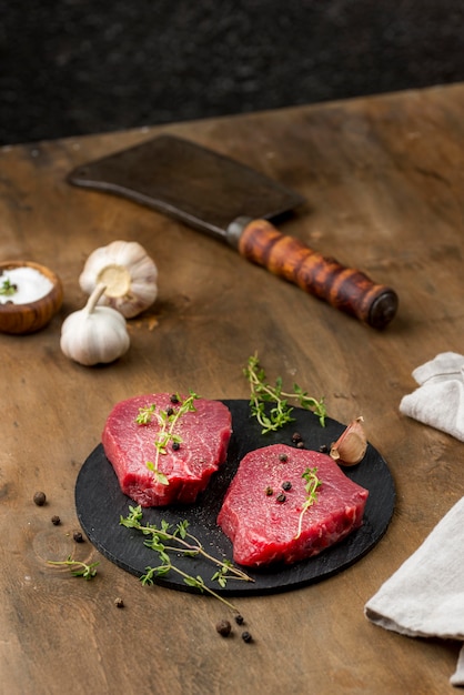 Free photo high angle of meat with herbs and cleaver