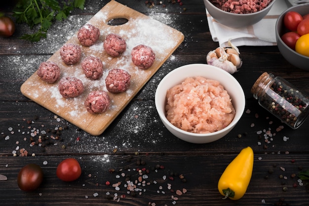 Free photo high angle meatballs on wooden board and minced meat