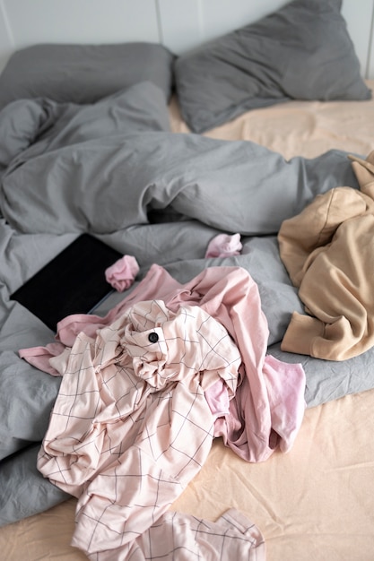 High angle messy bedroom with clothes on bed