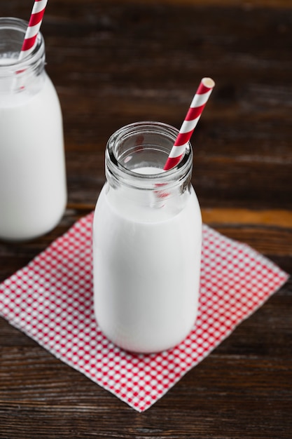 High angle milk bottle with straw on table