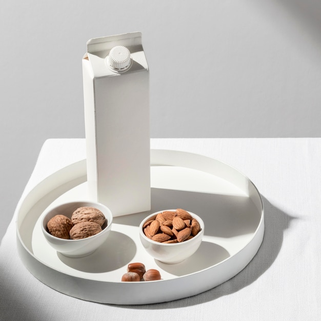 Free Photo high angle of milk carton on tray with almonds and walnuts