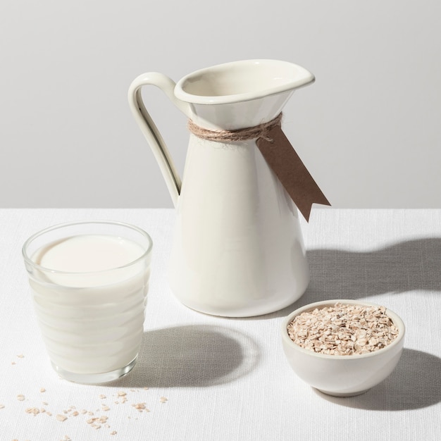 High angle of milk glass with jug and bowl of oatmeal