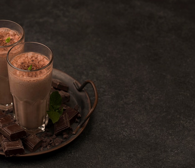 High angle of milkshake glasses on tray with chocolate and copy space