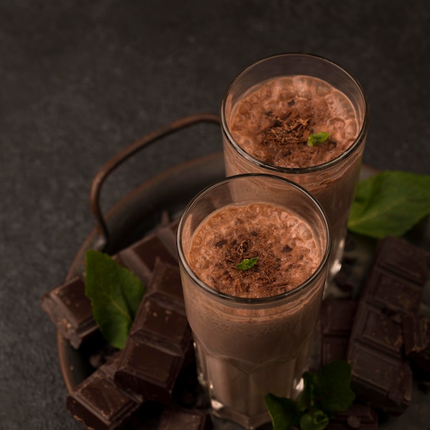 Free photo high angle of milkshake glasses on tray with mint and chocolate