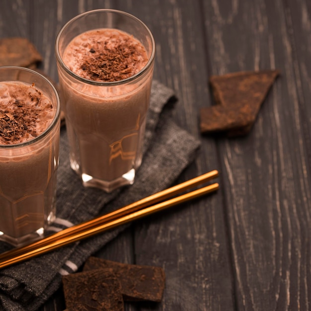 Free photo high angle of milkshake glasses with straws and chocolate