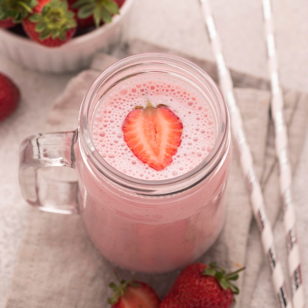 Free photo high angle of milkshake with strawberries and straws