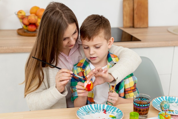 High angle mom helping son to paint eggs