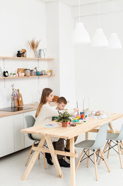 Free photo high angle mother and son at home painting eggs