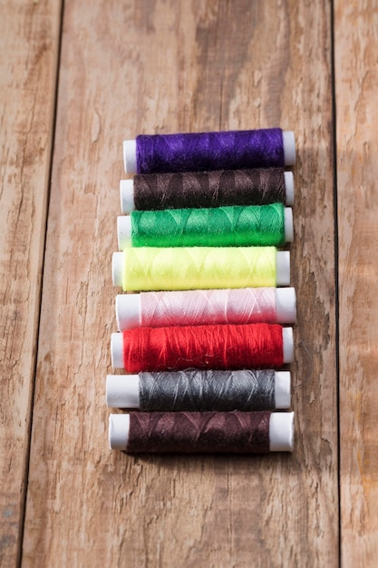 Free photo high angle of multicolored thread reels on wooden surface