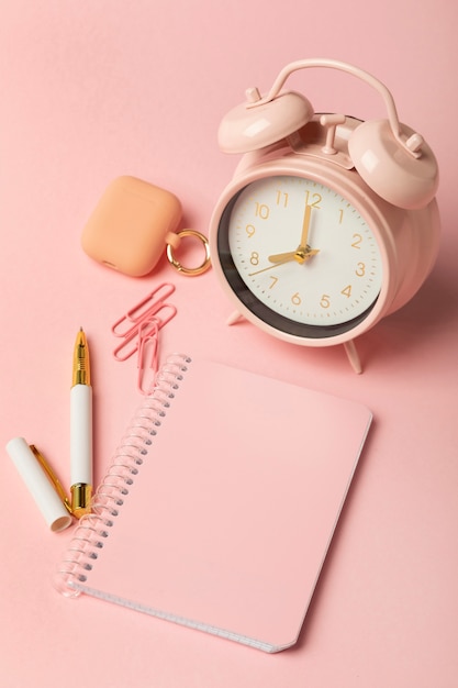 Free photo high angle notebook and clock arrangement