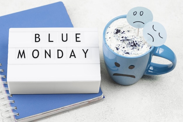 High angle of notebook with sad mug for blue monday